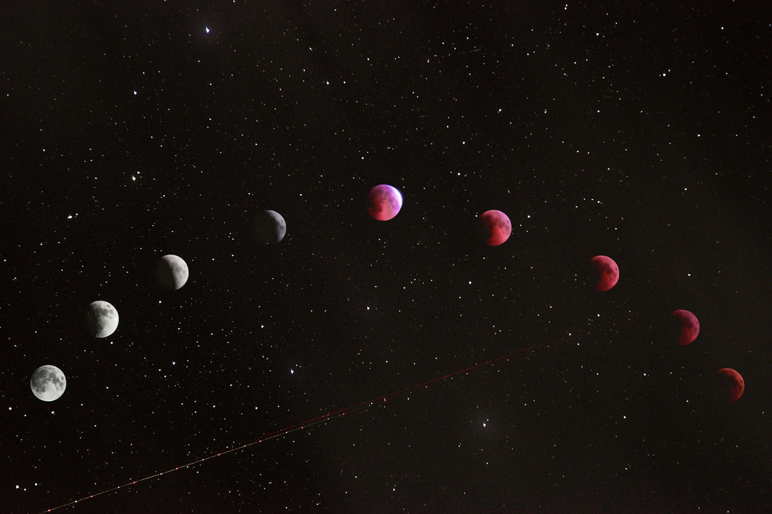 A sequence of lunar eclipse phases across a dark starry night sky