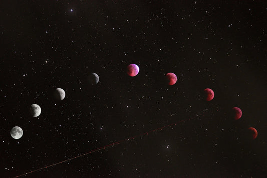 A sequence of lunar eclipse phases across a dark starry night sky