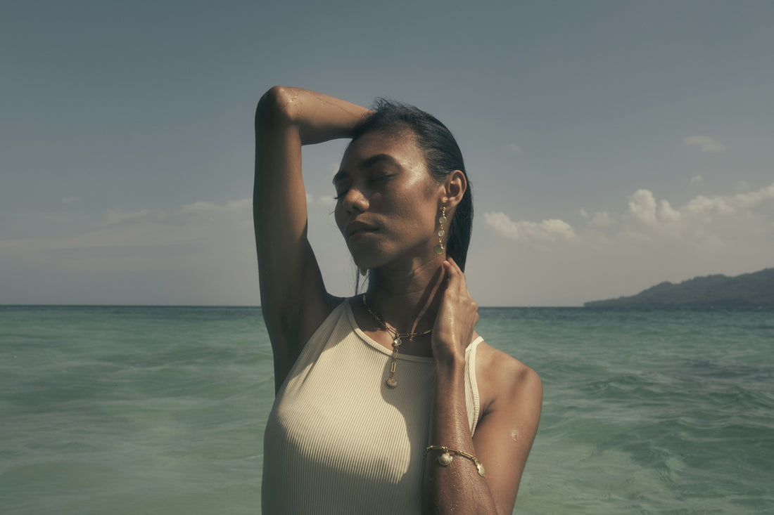 A woman standing in the ocean with her arms behind her head